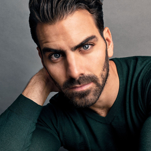 Headshot of Nyle DiMarco, a tan man with brown facial hair and head hair. he is wearing a green long sleeve sweater.